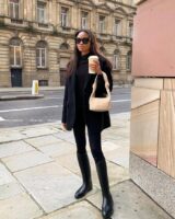 mulher jovem com calça legging com bota de cano longo, blazer e blusão de lã