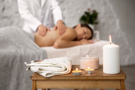 mulher deitada em spa com vela para massagem