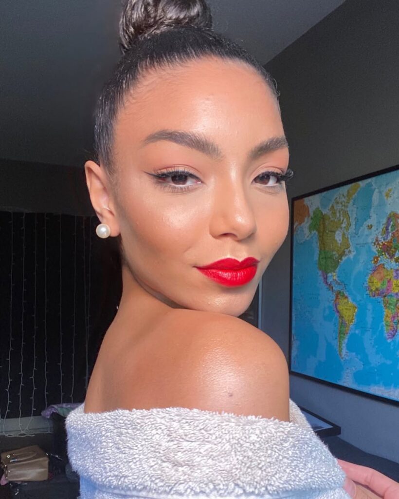 Mulher de pele preta, com cabelo preso e maquiagem com batom vermelho 