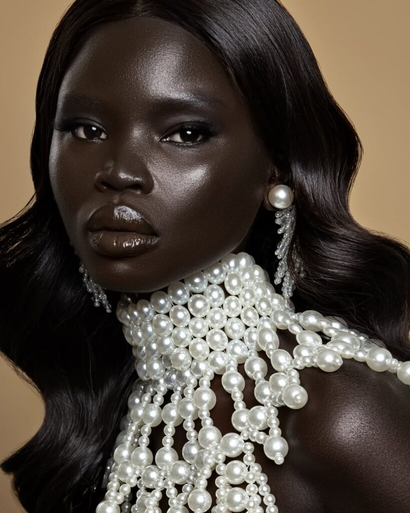 Mulher de pele preta, com roupa de pérolas e butter skin