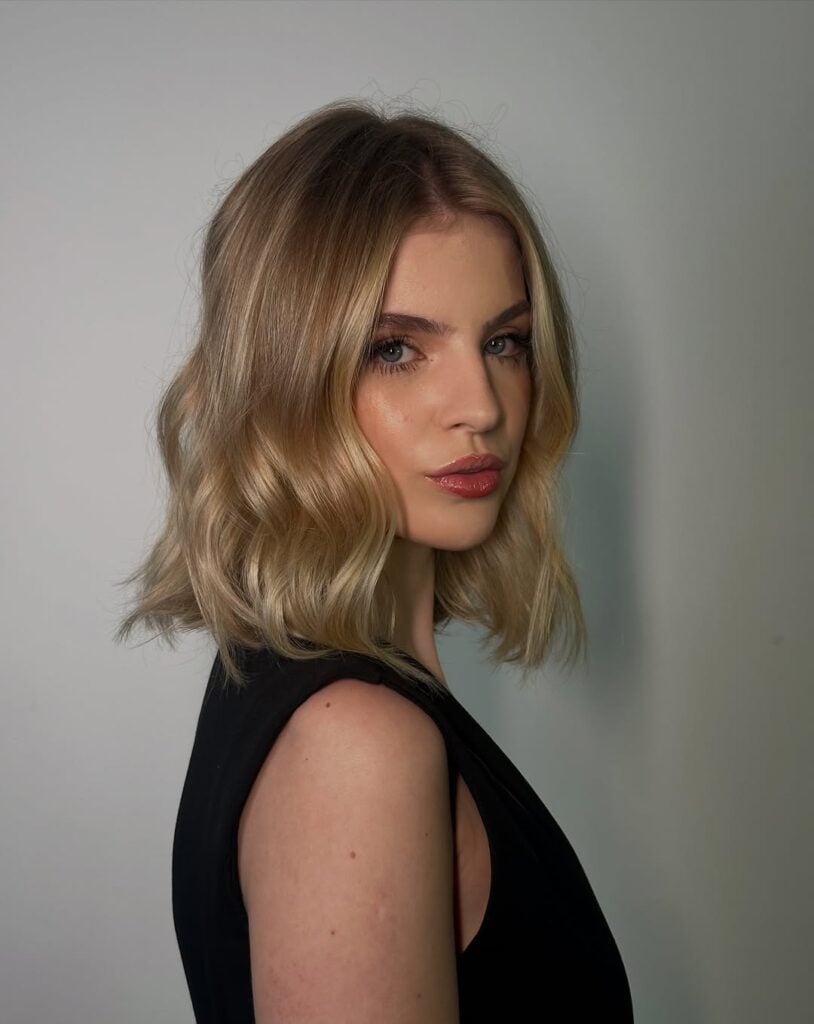 Mulher de pele clara, com roupa preta e cabelo bob curto loiro 