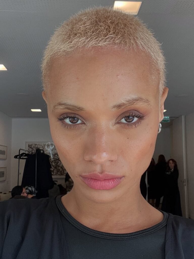 Mulher de pele preta, com cabelo curtíssimo loiro 