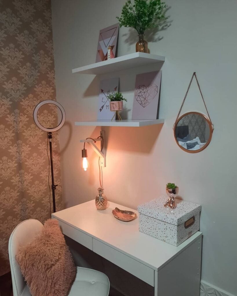 Cantinho com penteadeira e prateleiras brancas, poltrona com almofada rosa
