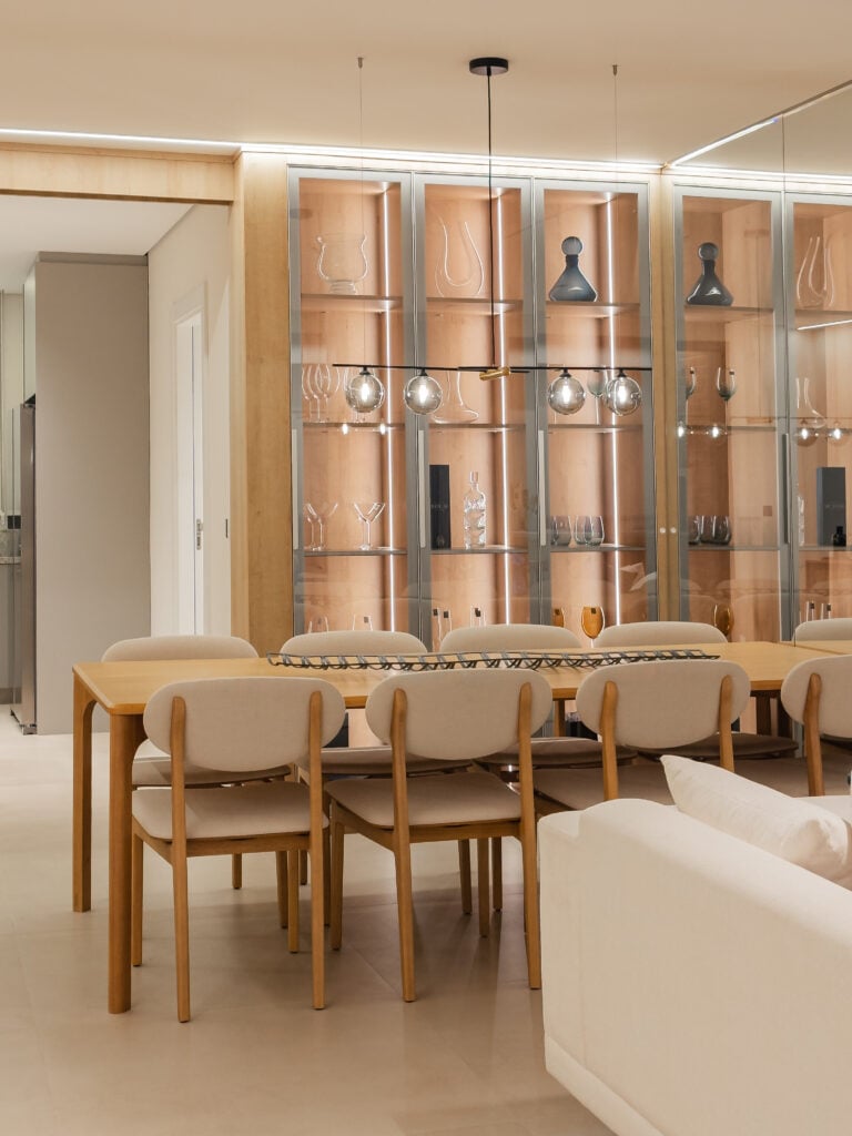 Sala de jantar com mesa retangular e estante com portas de vidro atrás