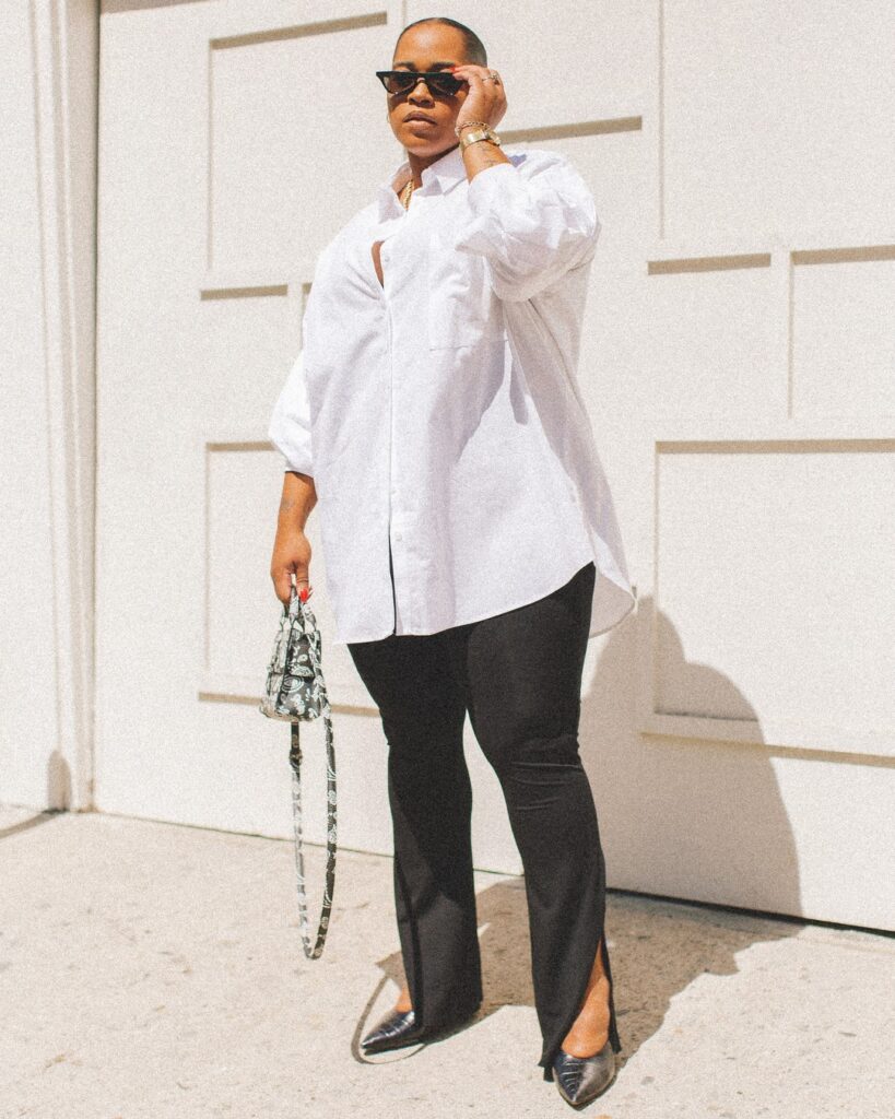 Mulher de pele preta, com calça legging preta e camisa branca