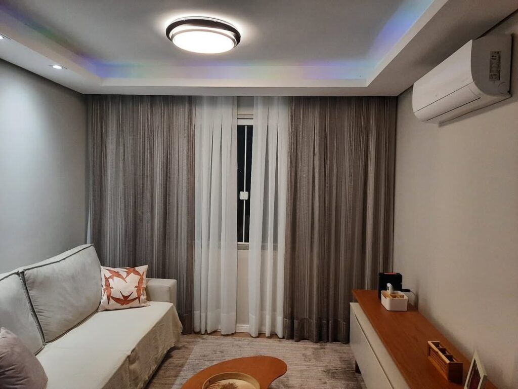 Sala de estar com sofá claro e cortinas cinza e branca