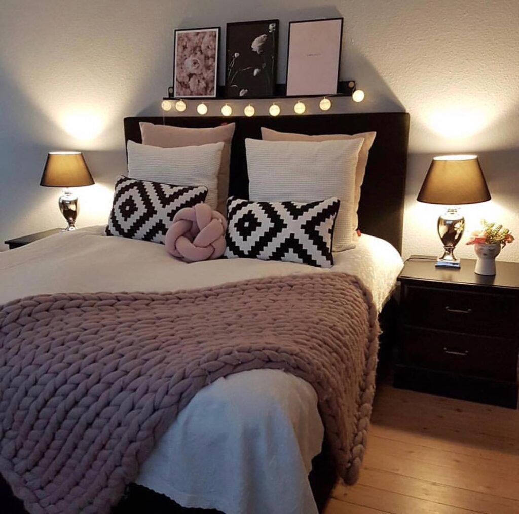 Quarto feminino com cabeceira e mesa de cabeceira pretas, almofadas rosa e brancas