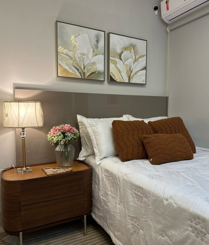 Quarto feminino com cabeceira cinza e mesa de cabeceira de madeira com abajur