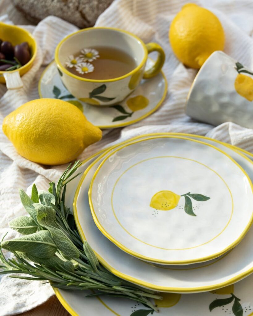 Jodo de pratos e xícara brancos com bordas amarelos de desenho de um limão siciliano