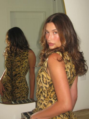 Hailey Bieber com vestido animal print, cabelo castanho e maquiagem guava