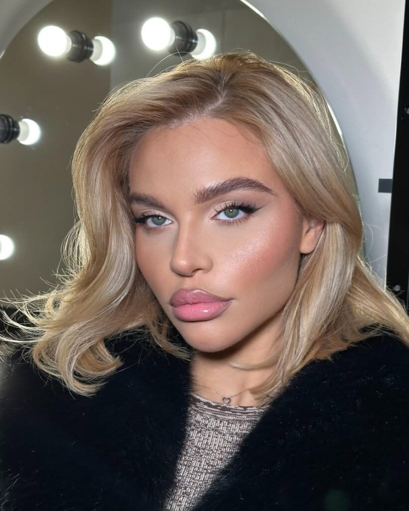 Mulher de pele clara, com cabelo loiro e maquiagem clean e gloss