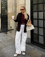 mulher jovem com look com jeans branco, tênis e casaco
