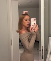 Mulher de pele clara, com vestido cinza e cabelo loiro