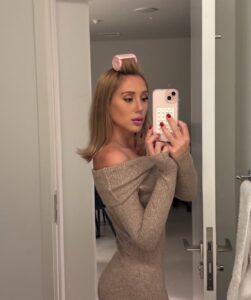 Mulher de pele clara, com vestido cinza e cabelo loiro