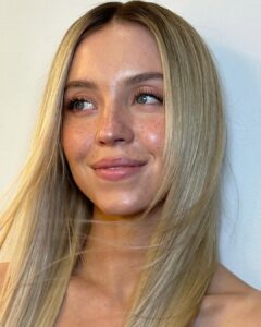 Sidney Sweeney, com cabelo loiro e maquiagem com sardas