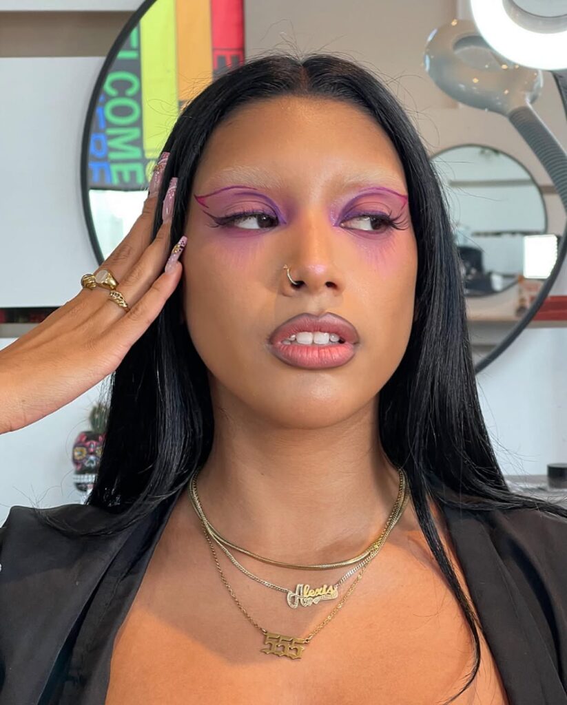 Mulher de pele "média", cabelo escuro, sobrancelha descolorida e delineado gráfico