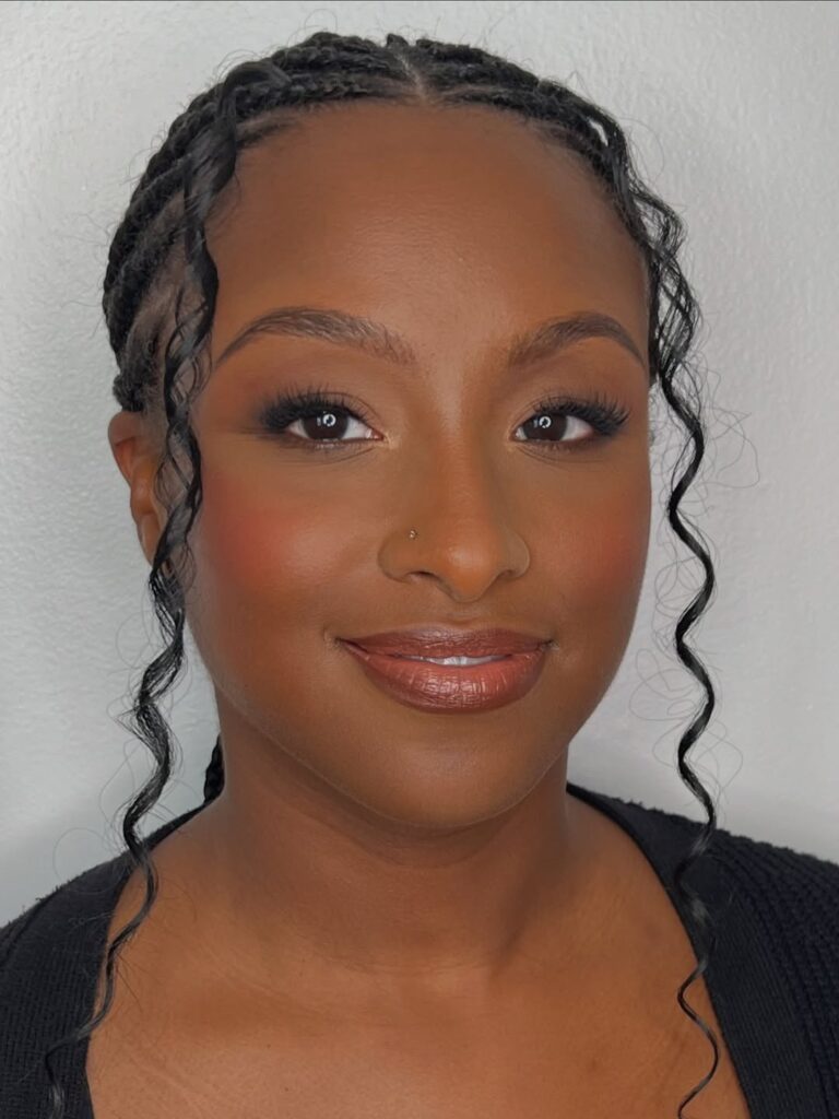 Mulher de pele preta, com cabelo trançado e maquiagem clean