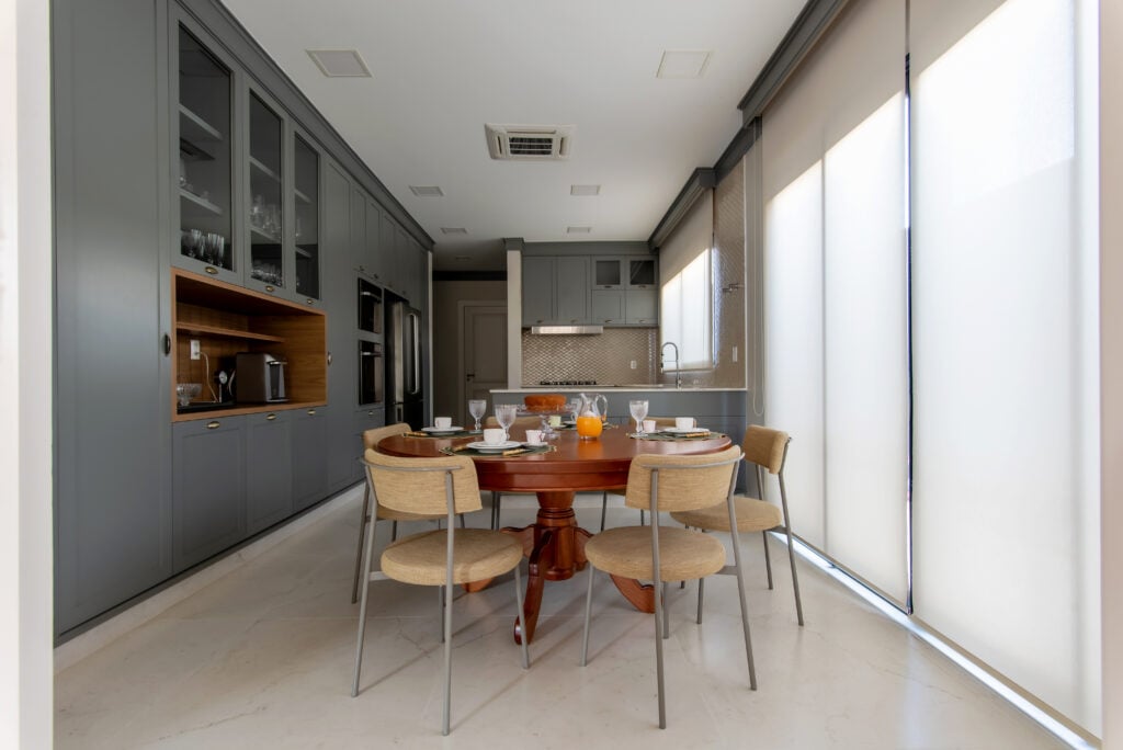 Cozinha no estilo provençal com armários cinza, puxadores em concha e mesa de madeira redonda