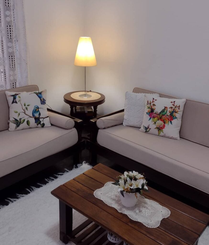 Sala com sofás claros e mesa de centro e lateral de madeira