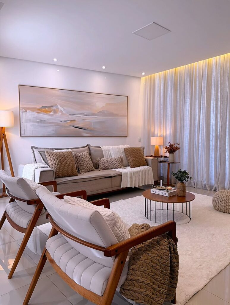 Sala de estar em tons neutros, sofá de linhas retas, poltrona de madeira com assento e encosto estofados