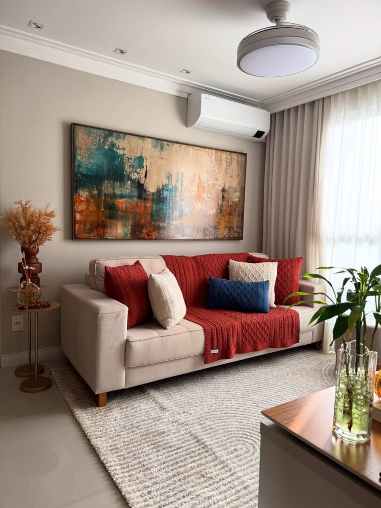 Sala de estar com sofá de linhas retas, manta e almofadas em tricô