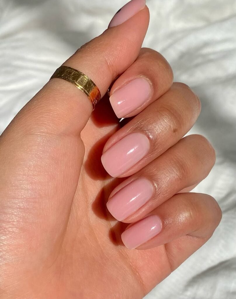 Mão de pele preta-clara, com anel em dourado e unha squoval tint
