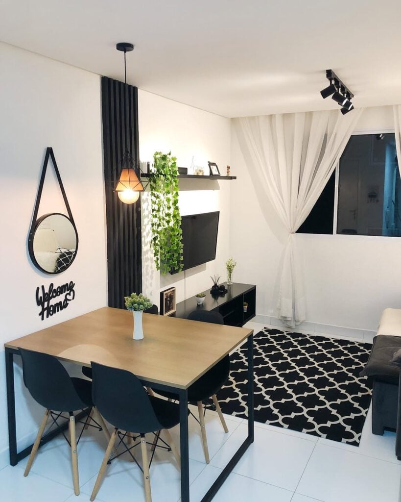 Sala de jantar e estar integradas com paredes brancas e um painel ripado preto