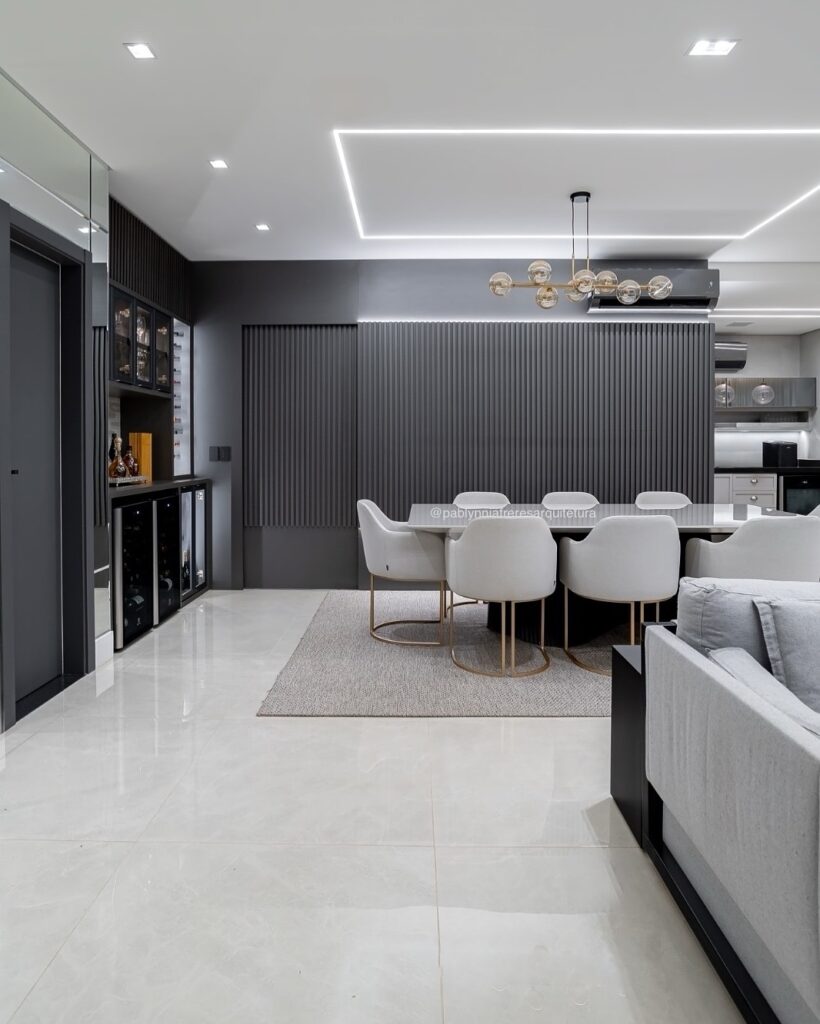 Sala de jantar com mesa retangular e poltronas claras e parede ripada preta