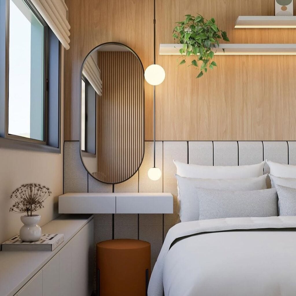 Quarto com cabeceira modular, espelho oval e penteadeira branca suspensa