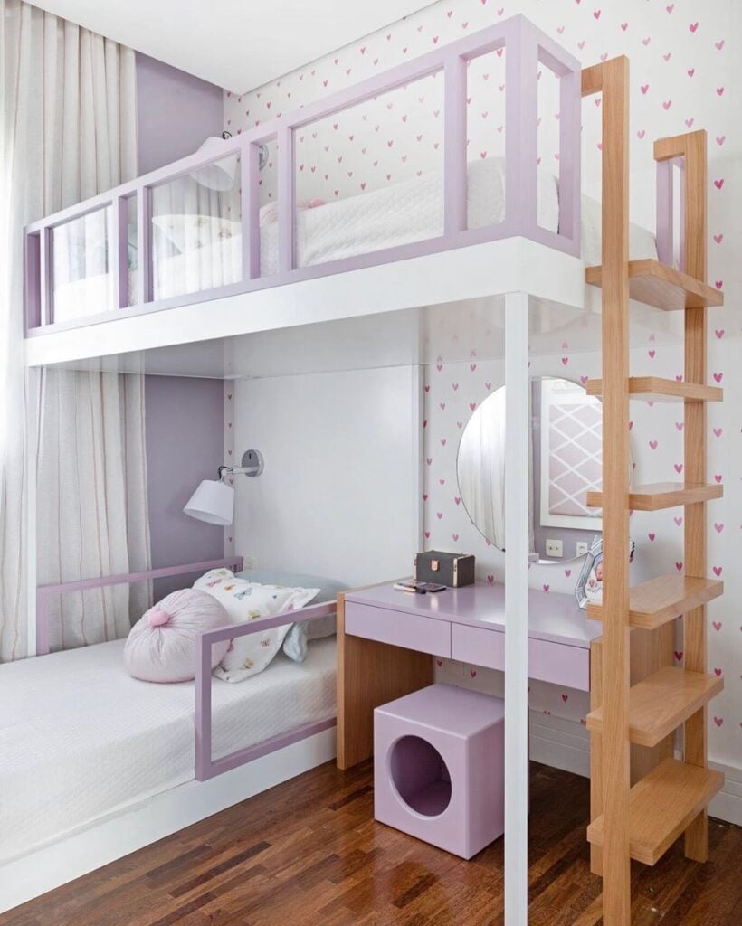 Quarto de criança com papel de parede branco e corações rosa, e beliche com escada