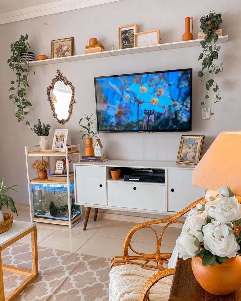Sala com cadeira de vime, balcão buffet branco e prateleira com quadros