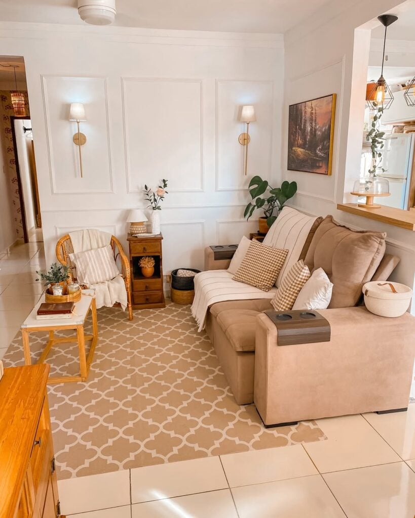 Sala de estar com sofá em tom de marrom claro, tapete grande e móveis de madeira