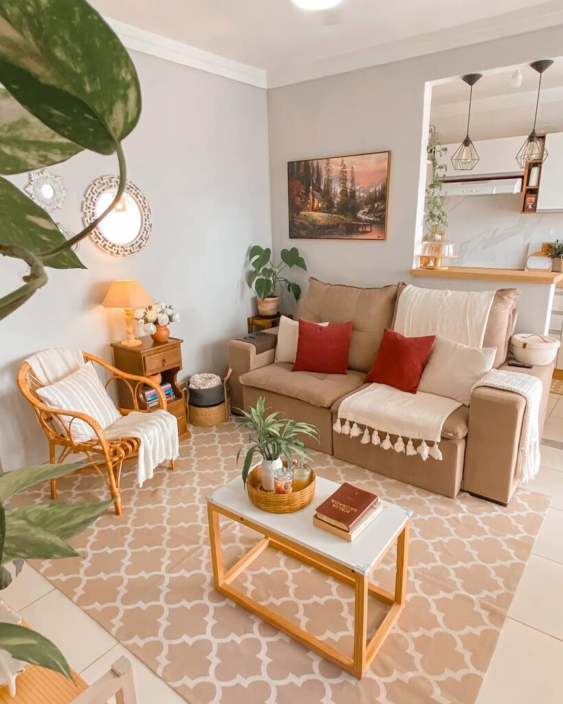 Sala de estar com sofá marrom claro e almofadas, cadeira de vime e tapete grande
