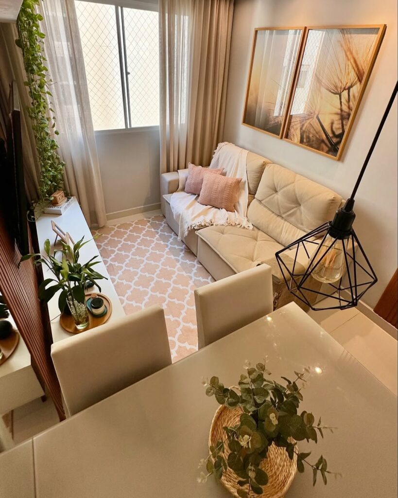 Sala pequena com sofá de dois lugares, quadros na parede e cortina