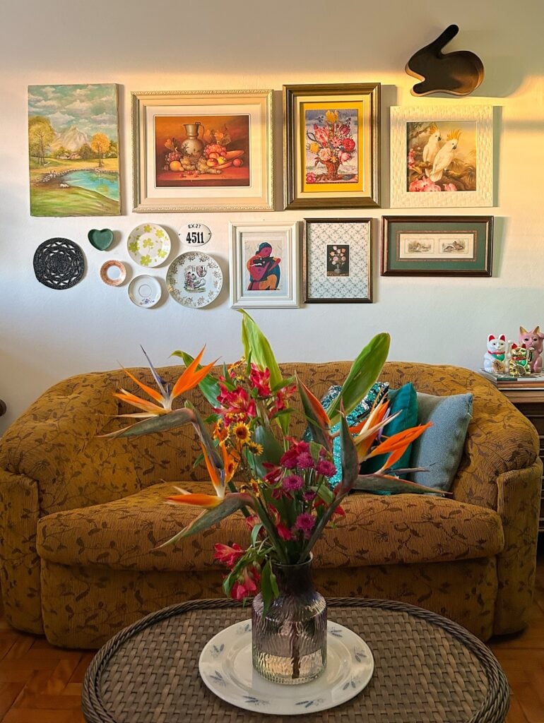 Sala de estar de casa de vó, com sofá, mesa de centro, quadros e flores