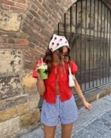 Mulher de pele clara, com blusa vermelha, show xadrez e cabelo castanho