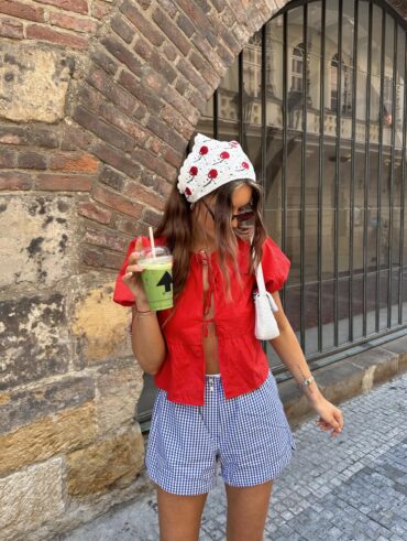Mulher de pele clara, com blusa vermelha, show xadrez e cabelo castanho