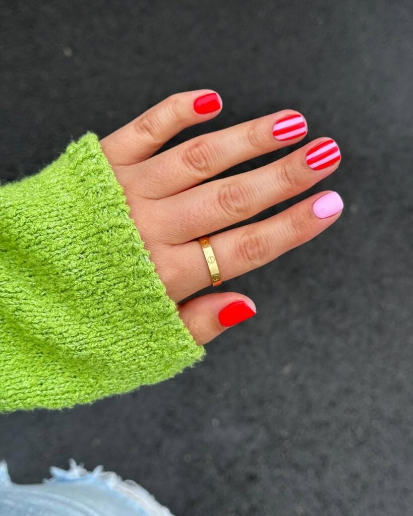 Mão de pele clara, com anel em dourado e unhas curtas decoradas