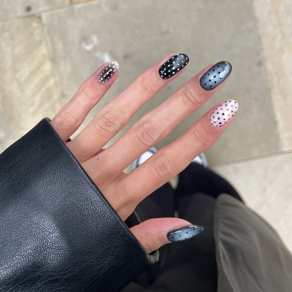 Mão de pele clara, com unhas decoradas. Aura, preta e branca com poá 