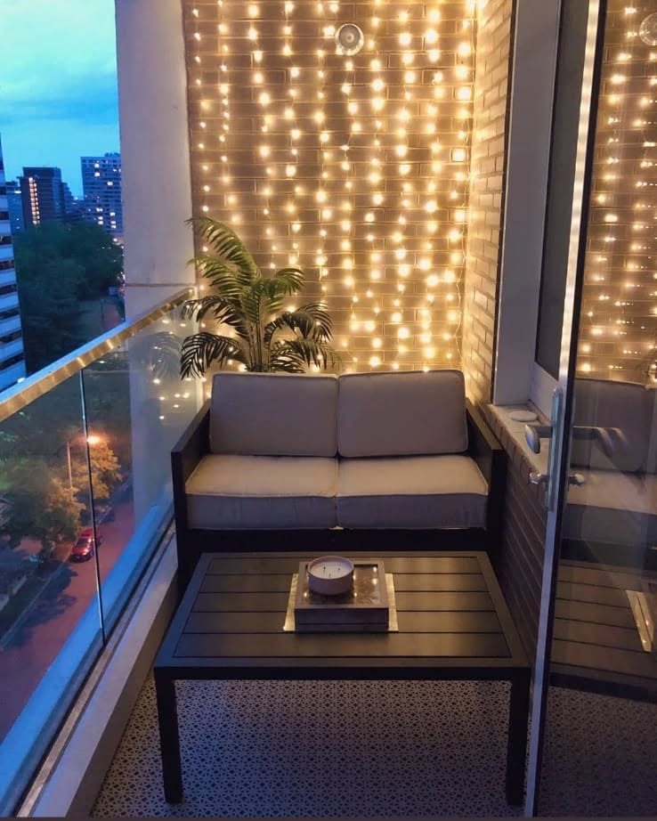 Mini varanda com sofá, mesa, planta e luzinhas