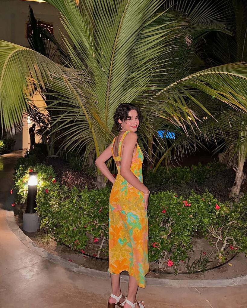 Mulher jovem e magra com vestido floral amarelo com flores verdes e laranjas