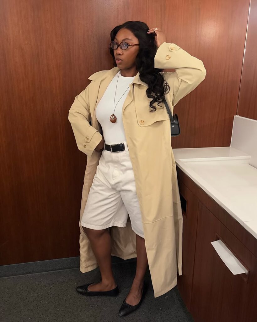 Mulher jovem com look branco, trench coat e sapatilha preta