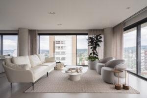 Sala de estar com sofás e poltronas claras e mesas de centro orgânicas