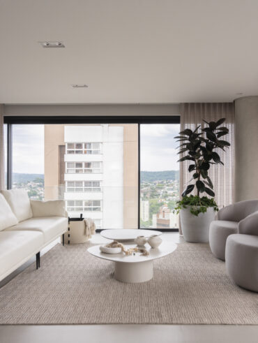 Sala de estar com sofás e poltronas claras e mesas de centro orgânicas