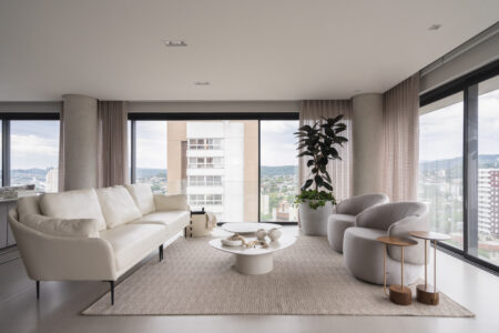 Sala de estar com sofás e poltronas claras e mesas de centro orgânicas