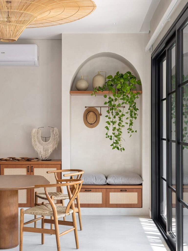 Arco embutido na arquitetura da parede com prateleira, plantas e banco com almofadas