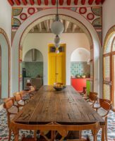 Casa com mesa de madeira retangular e grandes arcos nas portas e janelas