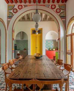 Casa com mesa de madeira retangular e grandes arcos nas portas e janelas