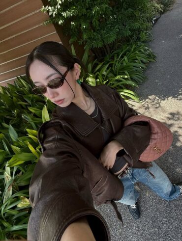 Mulher jovem com jaqueta de couro marrom, calça jeans e bolsa bolsa icarino