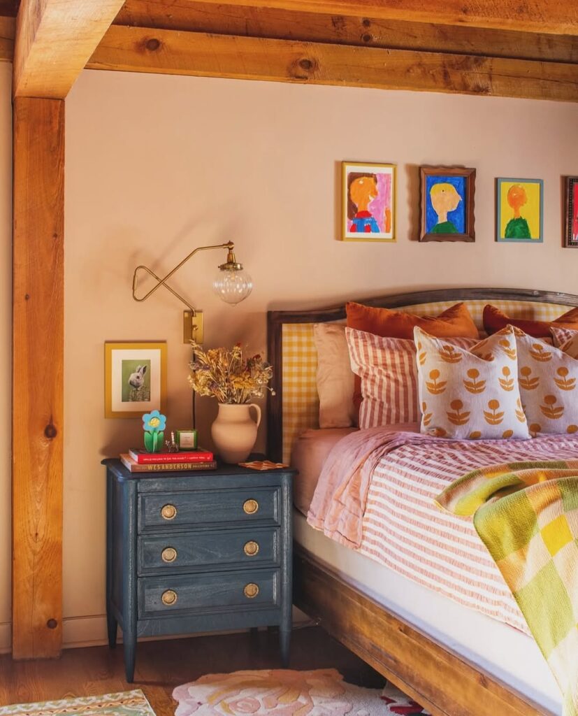 Quarto com cama de madeira, várias almofadas e quadrinhos coloridos acima da cabeceira
